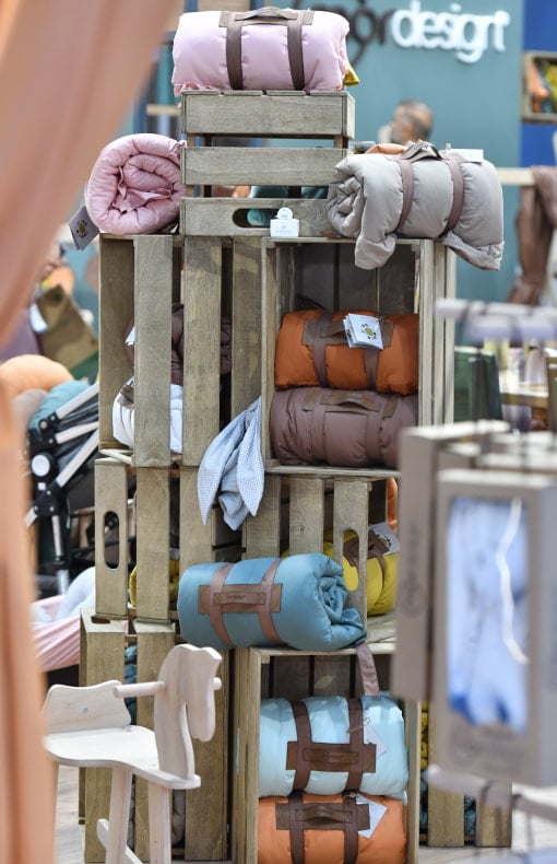 Stack of wooden crates filled with colorful rolled-up blankets at a home textile brand’s booth at CBME Türkiye.