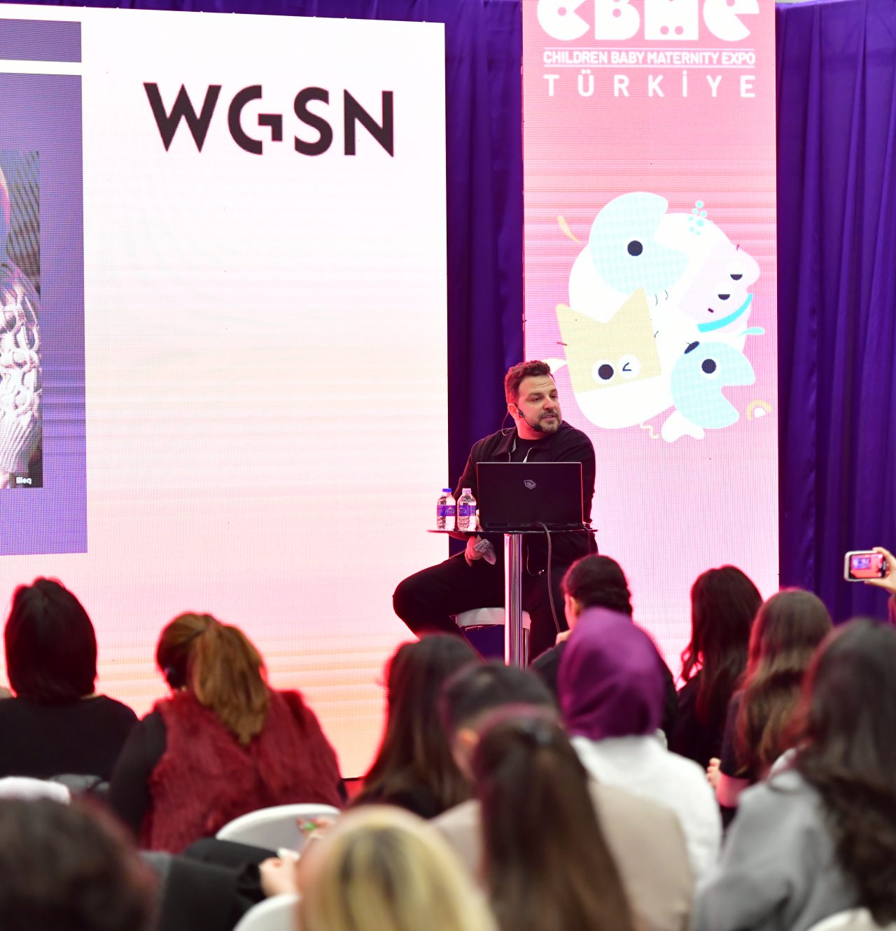 Three people discussing a blue garment at CBME Türkiye exhibition. Image 5 - Audience seated facing the WGSN Trend Seminar at CBME Türkiye.