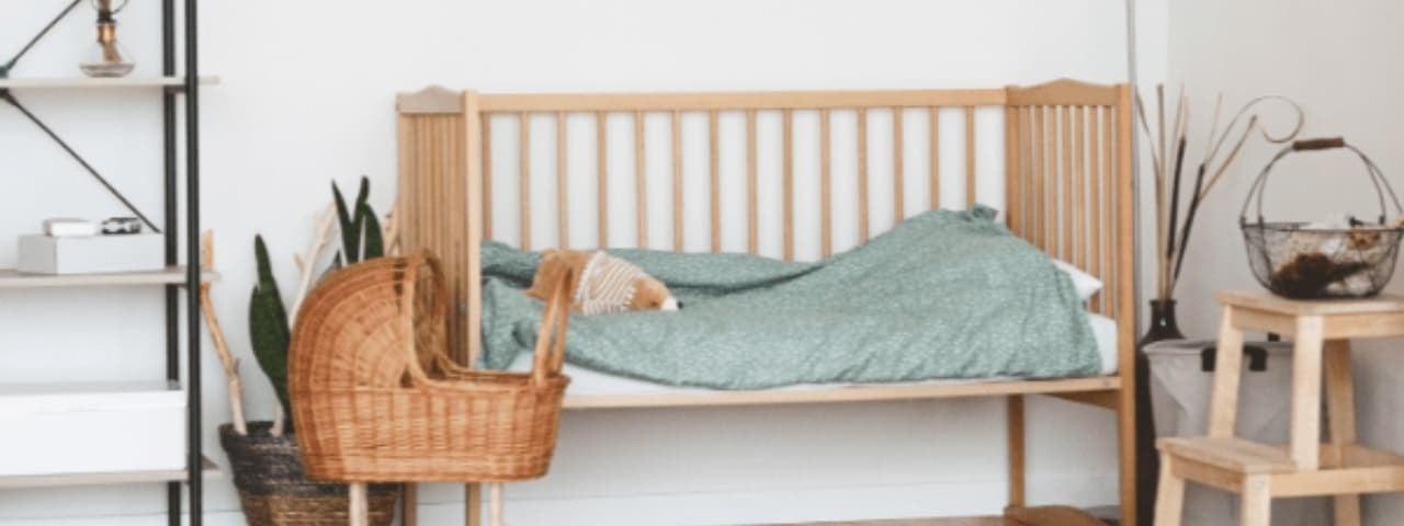 A child's room with a prominent wicker crib and a bed with wooden safety rails.