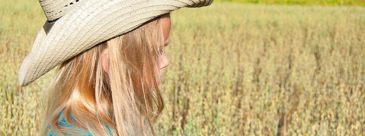  Close-up of a blonde girl in a straw hat in the countryside