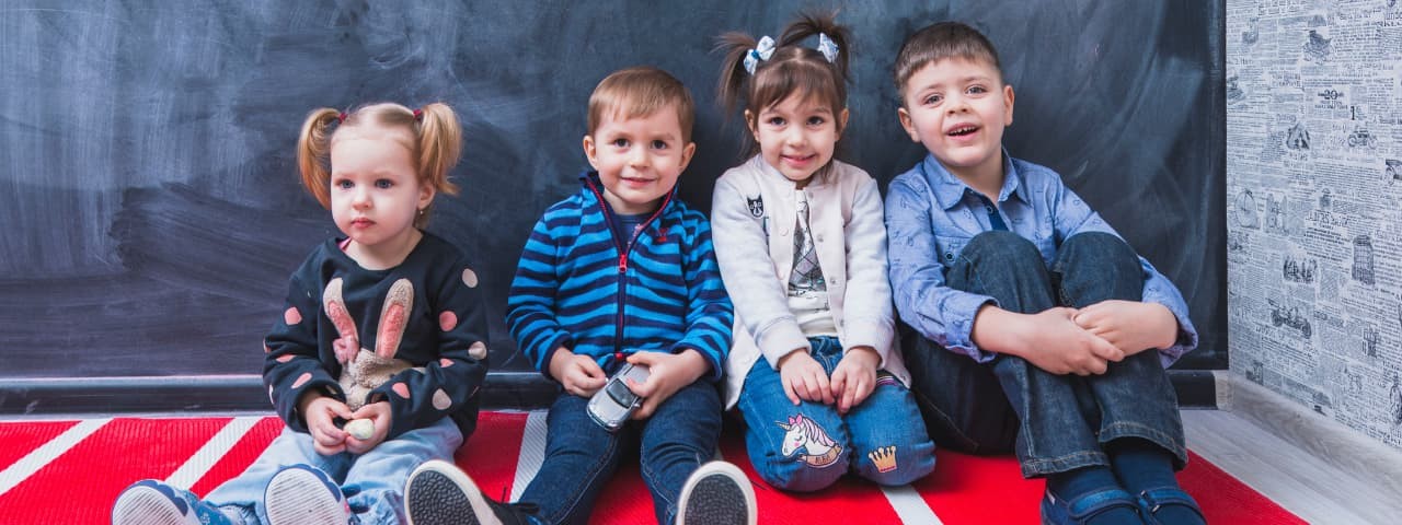  Three children sitting on the floor, posing for the camera.