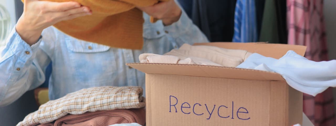  A person putting clothes into a cardboard box for recycling.